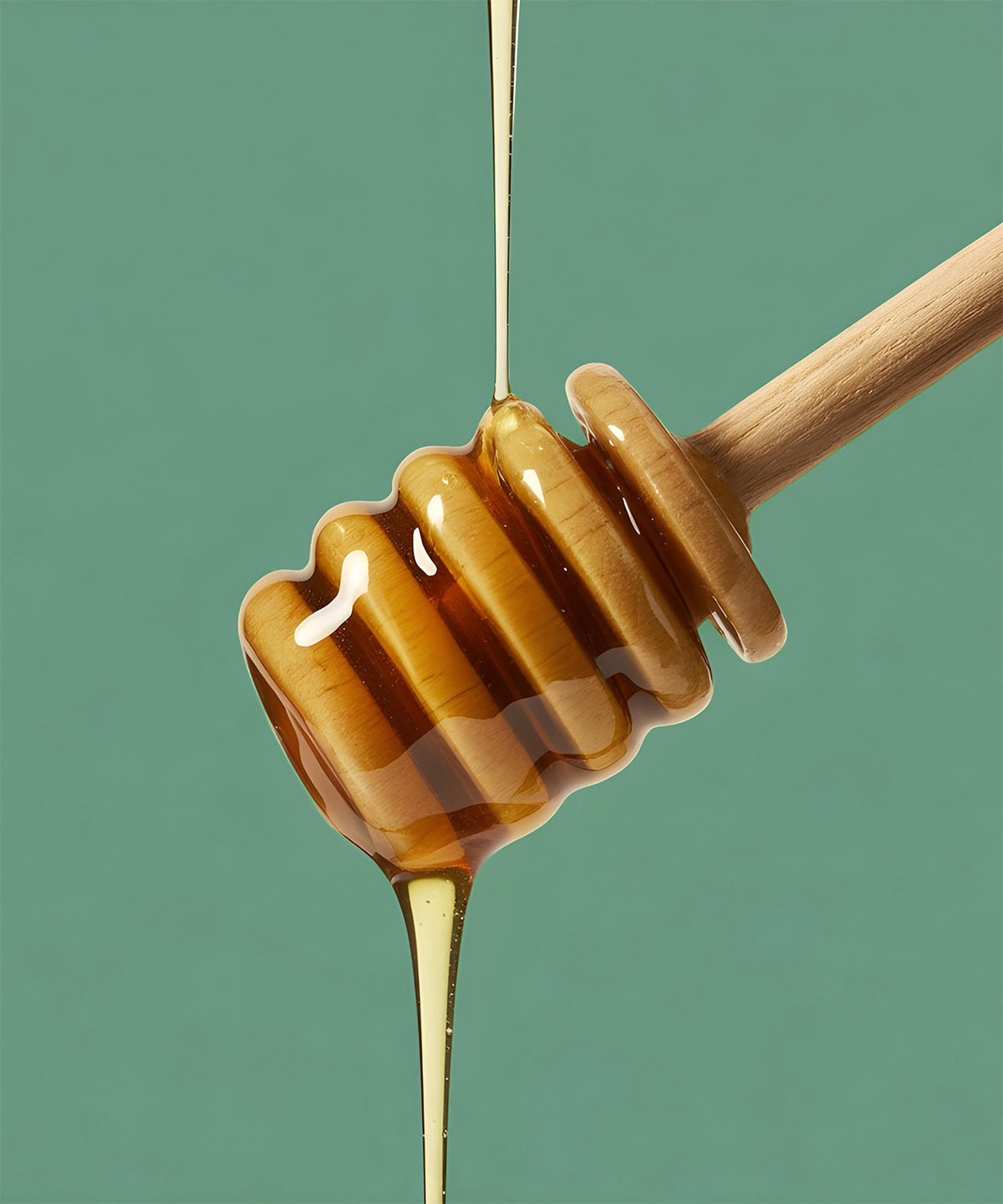 Golden manuka honey dripping from a honey dipper, an ingredient in NaturaLip\u00ae Restorative Balm